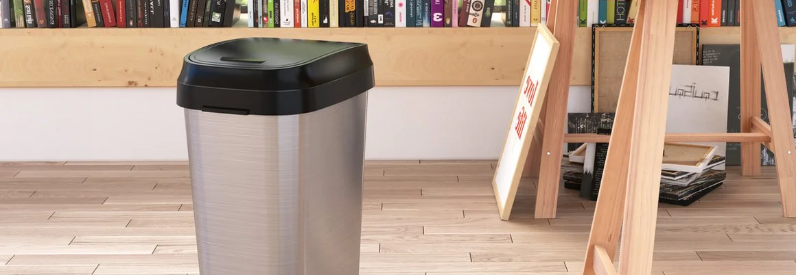 Ein silberner Mülleimer steht auf einem Holzboden.